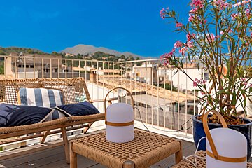 A balcony with wicker furniture and a potted plant with pink flowers