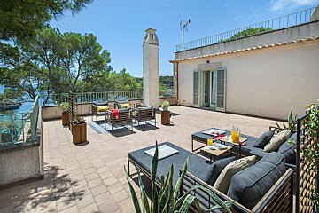 A balcony with a couch and chairs and a table with a magazine on it