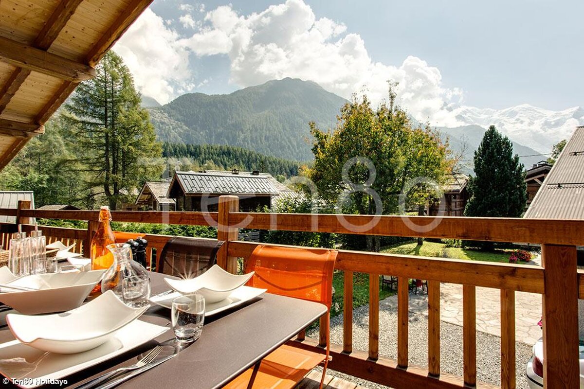 A balcony with a view of mountains and a bottle of orange juice