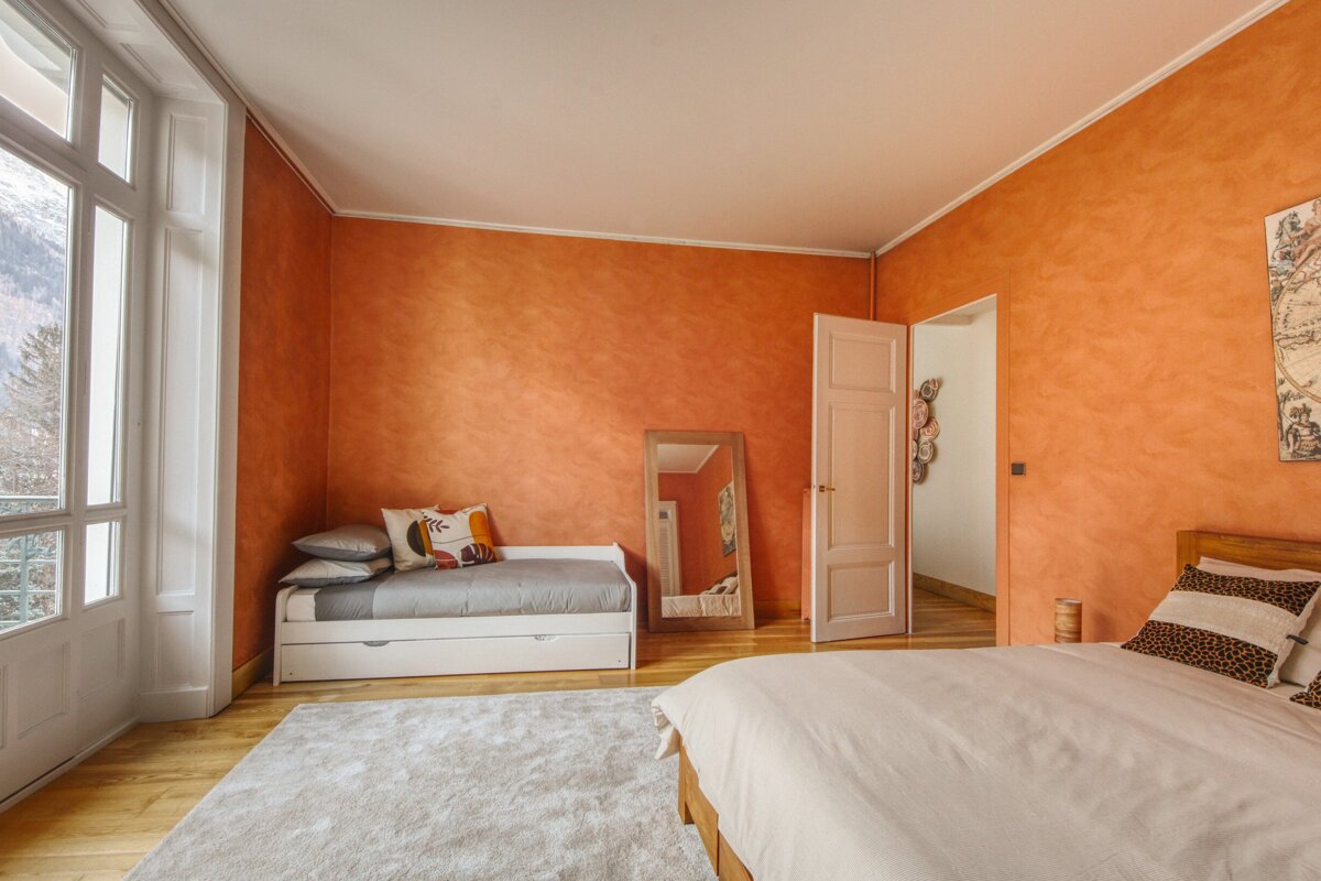 A bedroom with orange walls and a white bed