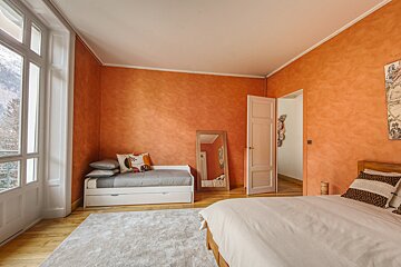 A bedroom with orange walls and a white bed