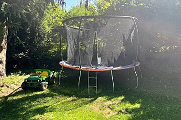 A john deere tractor sits next to a trampoline