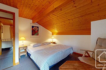 A bedroom with a bed and a chair and a sign that says alpine-pr