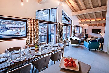 A dining room table with a bottle of wine on it