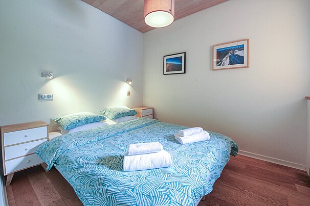 A bedroom with a bed and two pictures on the wall