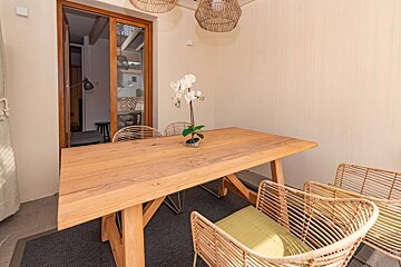A wooden table with wicker chairs and a plant on it