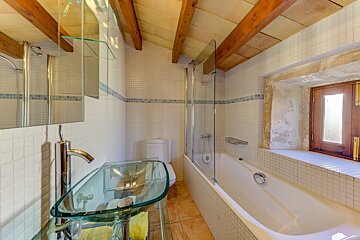 A bathroom with a glass sink and a bathtub