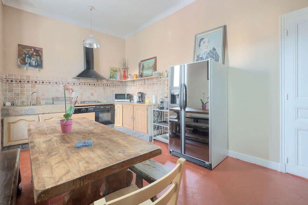 A kitchen with a stainless steel refrigerator and a wooden table