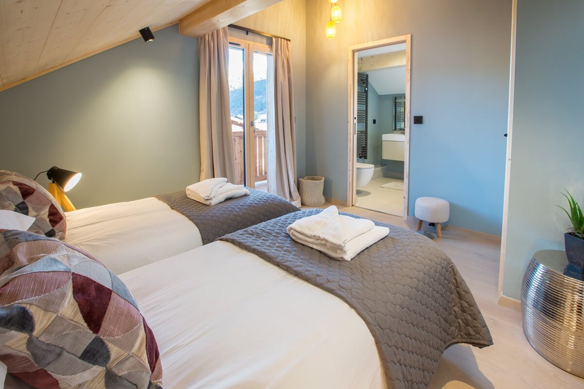 A bedroom with two beds and a bathroom in the background