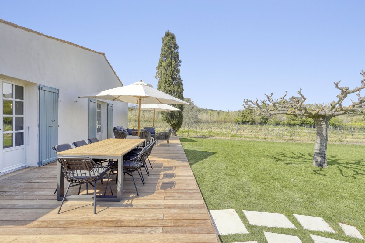 A wooden deck with a table and chairs and umbrellas