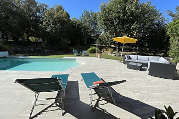 A patio with chairs and an umbrella next to a pool