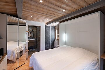 A bedroom with a bed and a mirrored wall