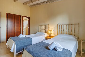 A bedroom with two beds and a lamp on the nightstand