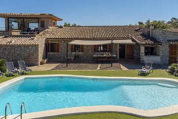 A large swimming pool in front of a stone house
