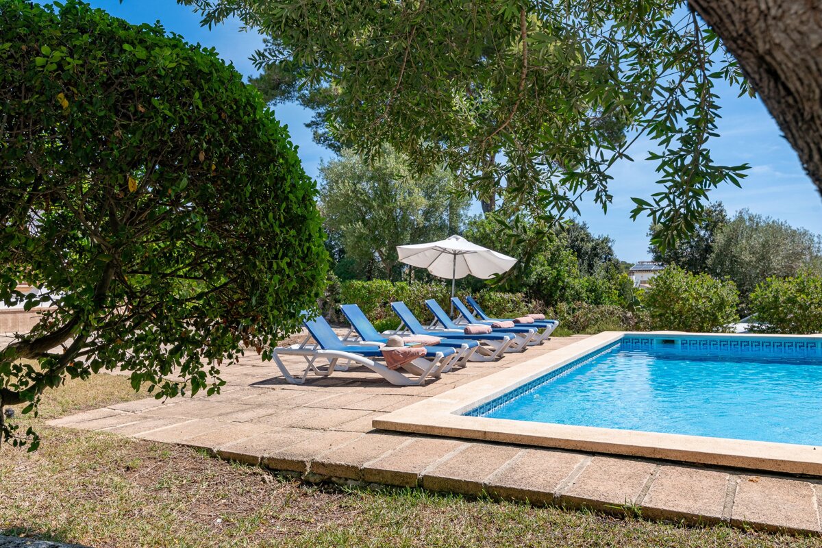 A swimming pool with chairs and umbrellas around it