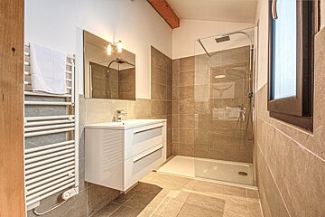 A bathroom with a walk in shower and a sink