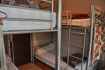 Several metal bunk beds with white mattresses and brown quilts in a hostel-style room.