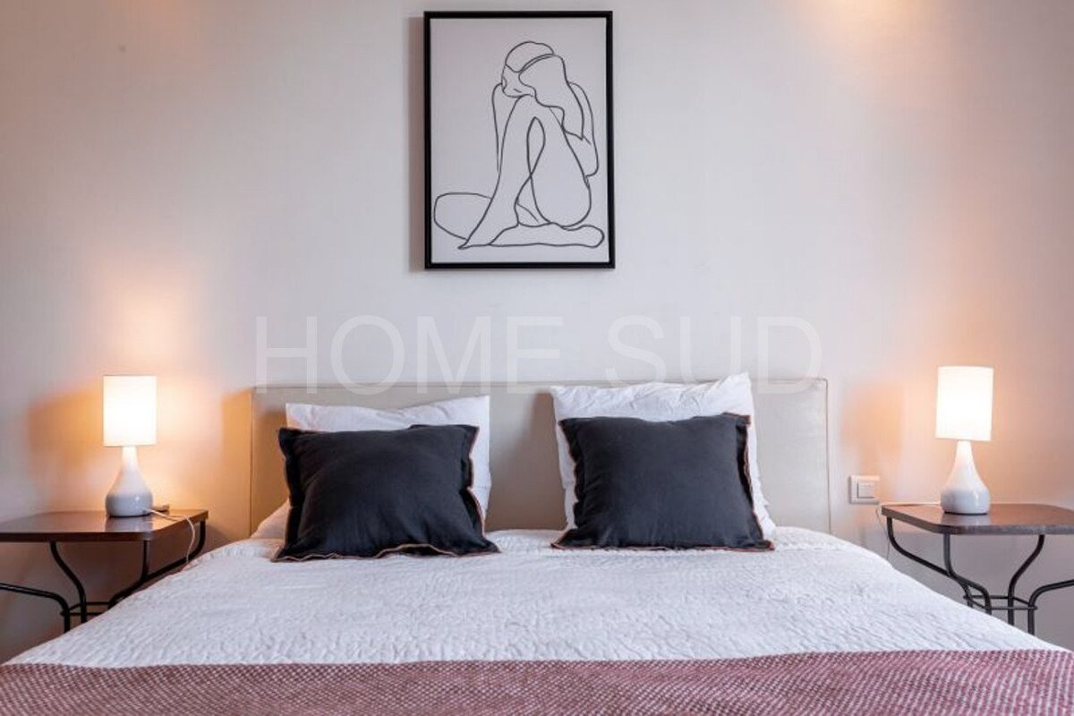 A bedroom with a picture of a woman on the wall above the bed