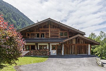 A large wooden house with mountains in the background