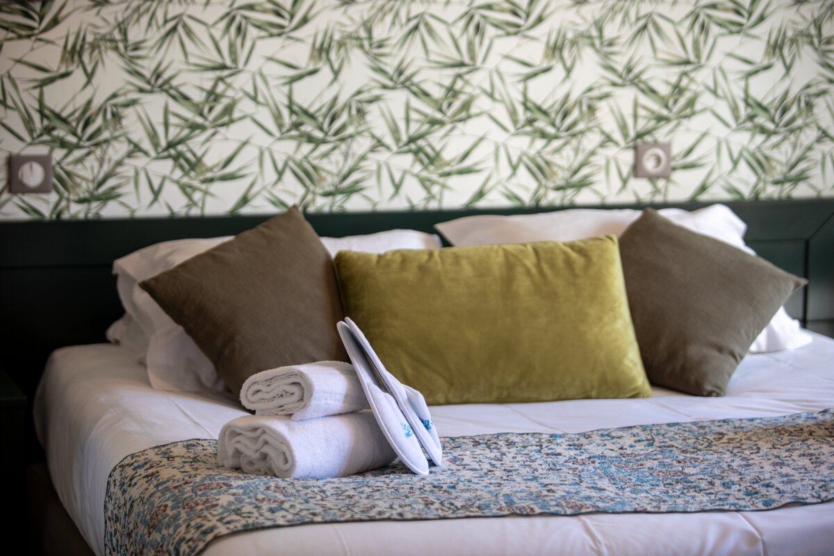 A bed with a green pillow and white towels on it