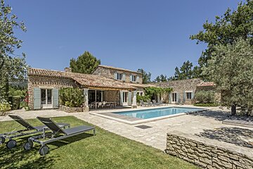 A large stone house with a large swimming pool in front of it