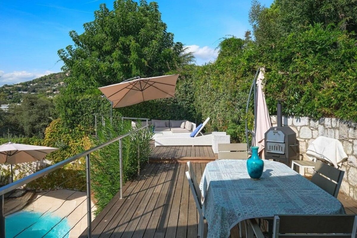 A wooden deck with a table and chairs and umbrellas