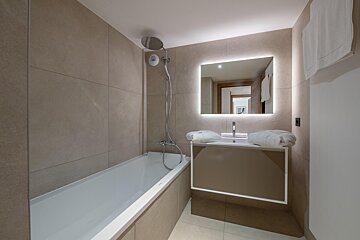 A bathroom with a bathtub a sink and a mirror