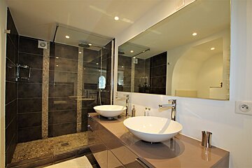 A bathroom with two sinks and a walk in shower