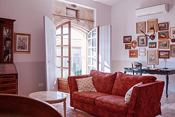 A living room with a red couch and paintings on the wall
