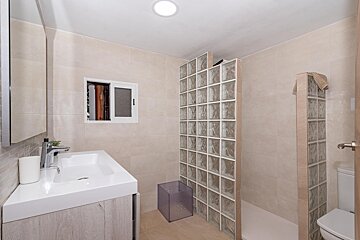 A bathroom with a glass block shower and a sink