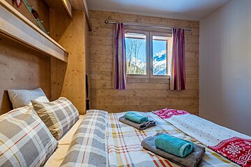 A bedroom with a bed and a window with mountains in the background
