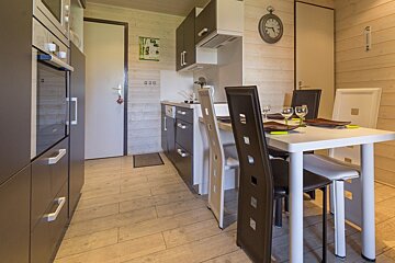 A kitchen with a table and chairs and a clock on the wall