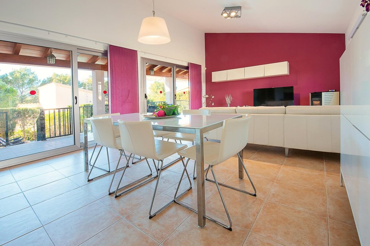 A dining room with a table and chairs and a pink wall