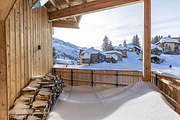 A wooden balcony with a view of a snowy village