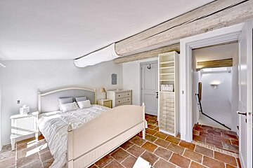 A bedroom with a white bed and a dresser