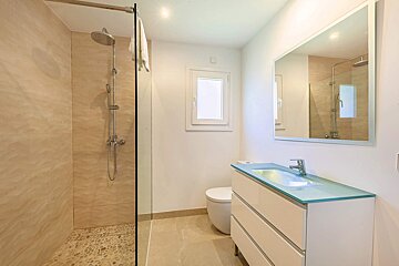 A bathroom with a walk in shower and a sink