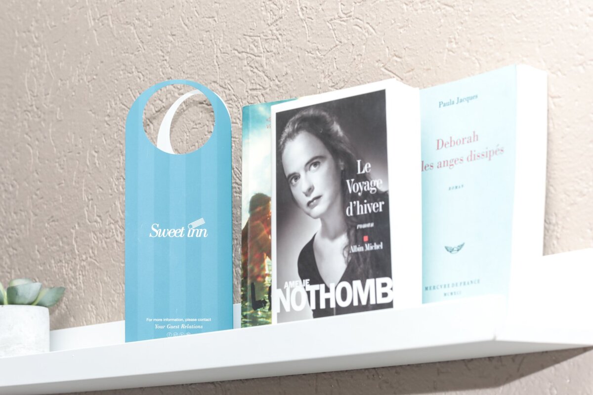 Three books on a shelf including one by nothomb