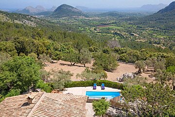 An aerial view of a lush green valley with mountains in the background