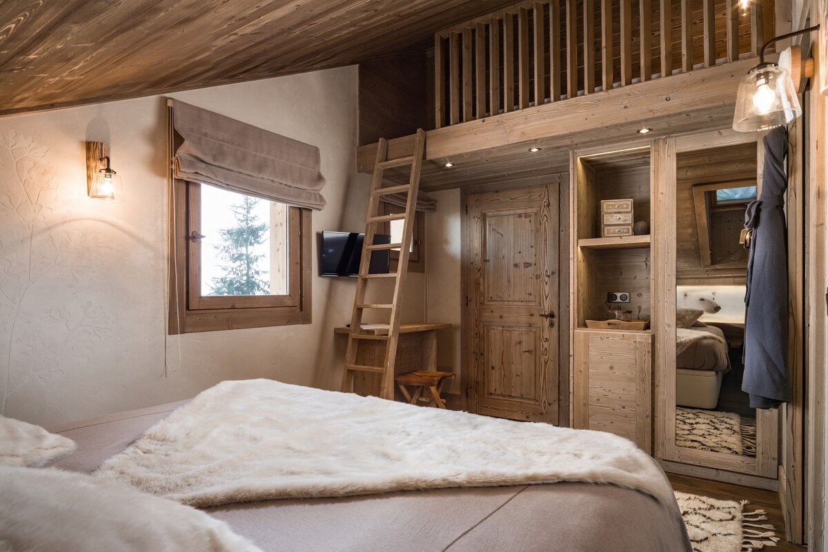 A bedroom with a ladder leading up to a loft