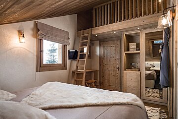 A bedroom with a ladder leading up to a loft