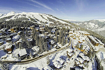 An aerial view of a snowy ski resort with mountains in the background