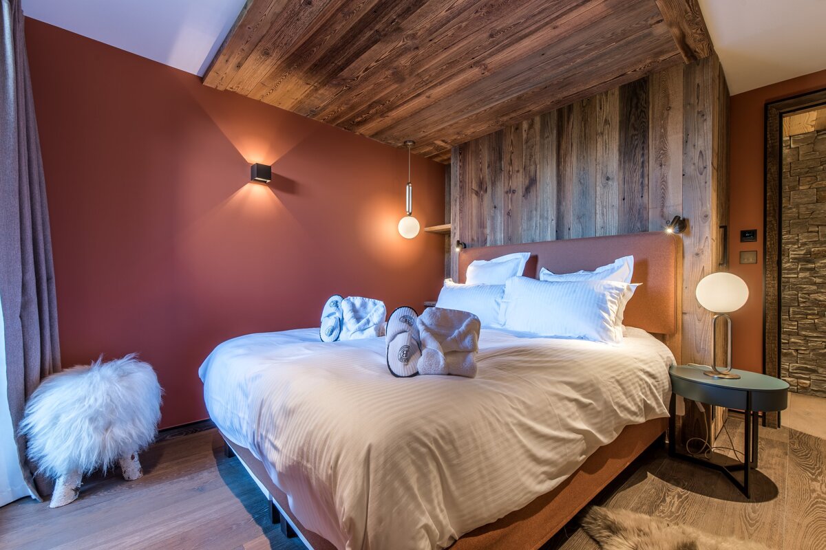 A bed in a hotel room with a red wall