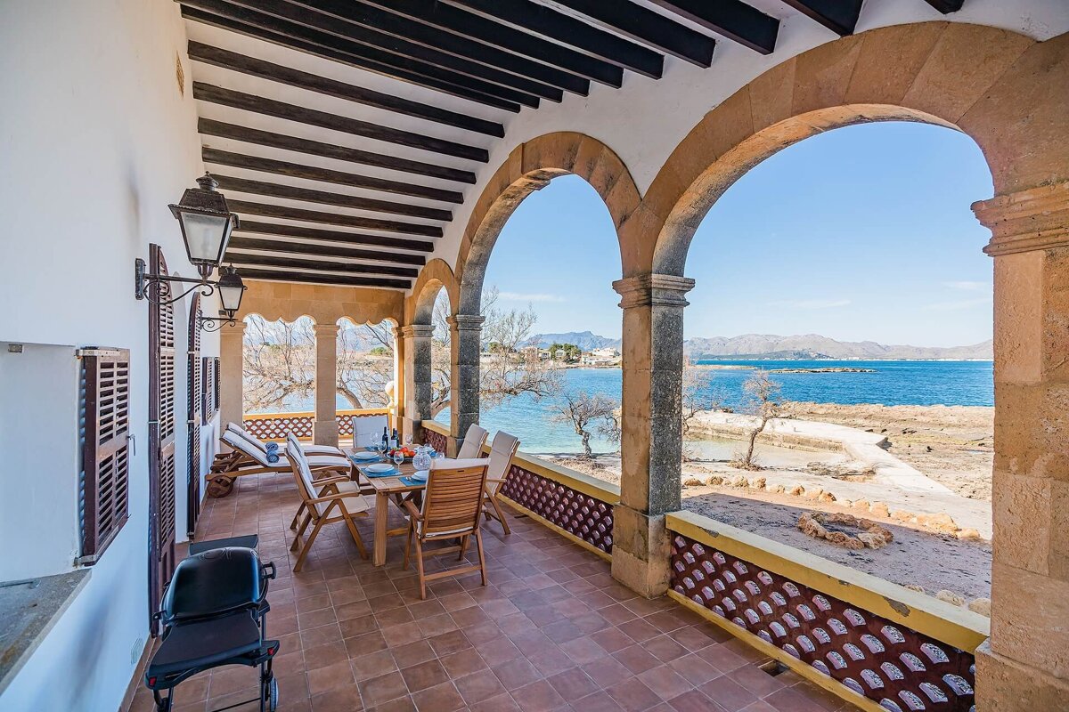 A balcony with a table and chairs overlooking the ocean