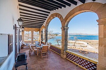 A balcony with a table and chairs overlooking the ocean