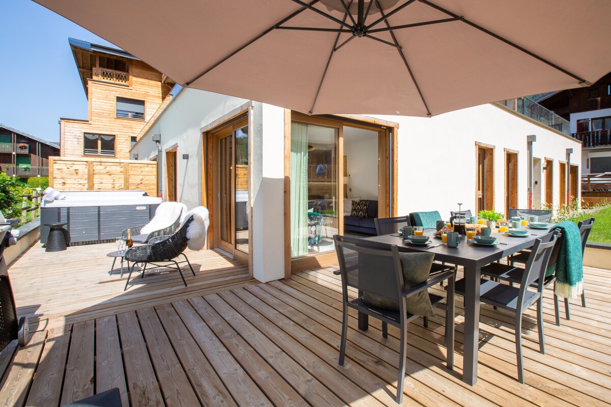 A wooden deck with a table and chairs under an umbrella