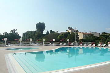 A large swimming pool surrounded by chairs and umbrellas