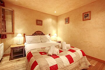 A bedroom with a bed with a red and white quilt