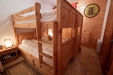 A picture of a teddy bear hangs above a bunk bed