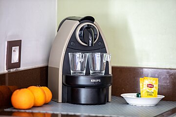 A krups coffee maker sits on a counter next to oranges
