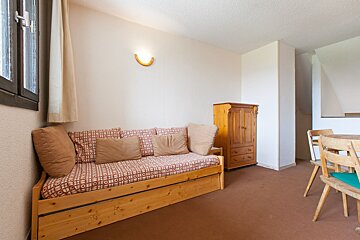 A living room with a wooden couch and chairs